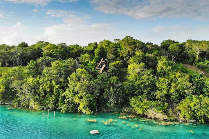 Vue aérienne de la rive turquoise de la lagune de Bacalar et de la jungle d’où émergent les cabanes d’Azul Nomeolvides.