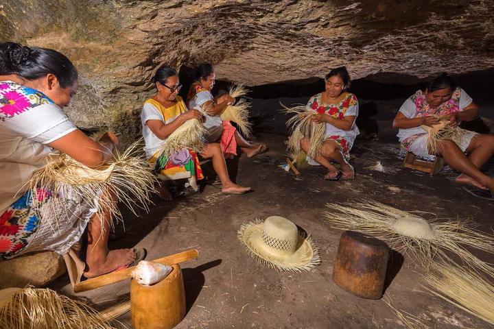 Five weavers working jipi fiber in a cave in Becal, with half-woven hats at their feet.