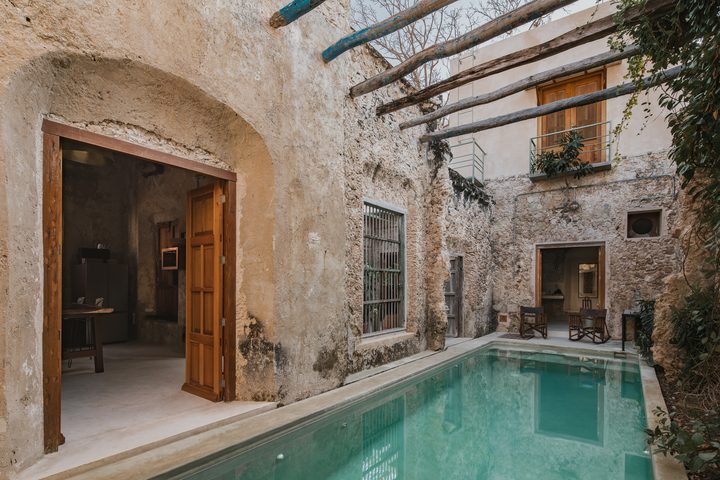 Patio of Casa Zotz, one of the Casonas MX casonas: a pool between old stone walls, wooden beams and doors open to the rooms.