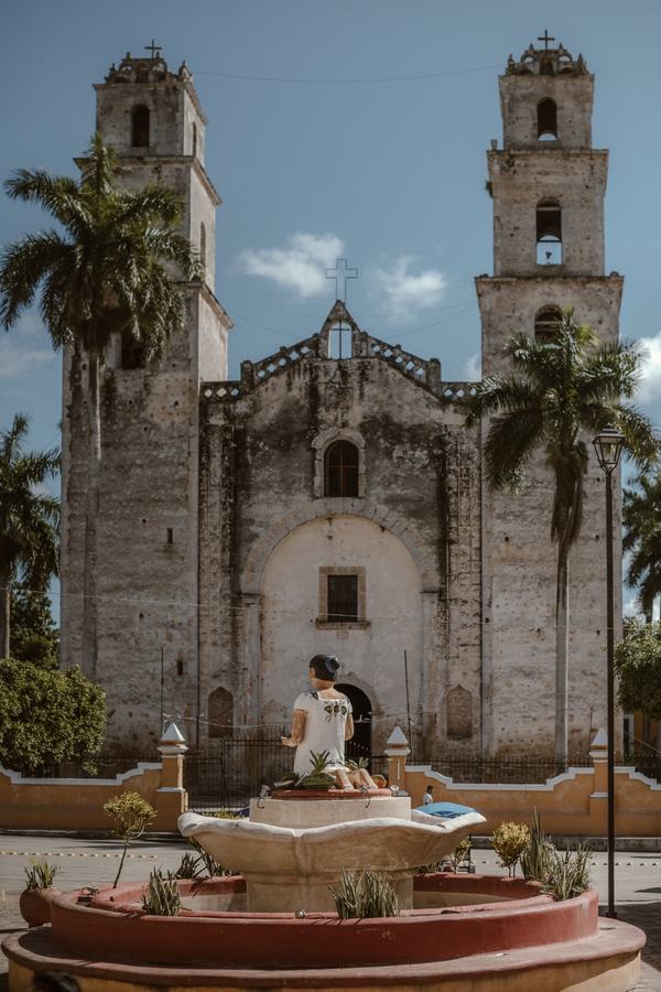 La iglesia de Espita, con sus dos torres, vista desde la fuente de la plaza entre palmeras.