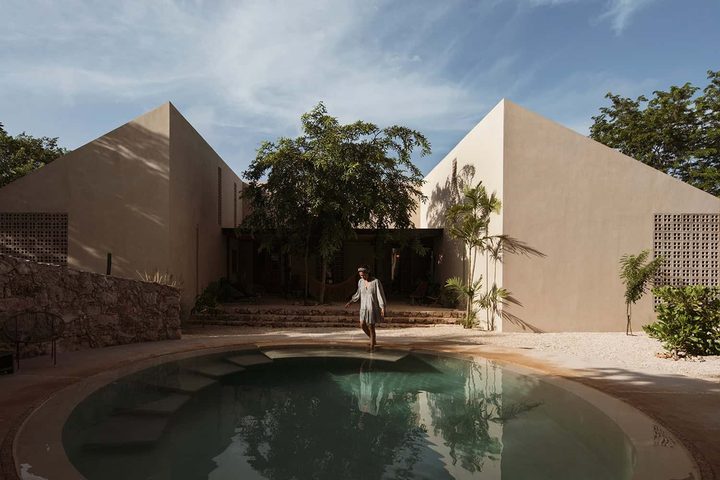 La piscine ronde de Galopina devant deux volumes à toit à deux pentes, entourés de végétation.