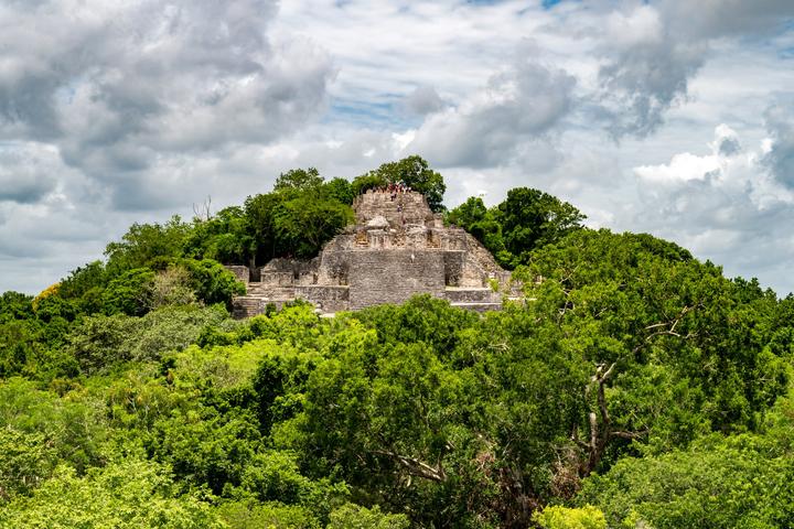 Structure II at Calakmul rises above the jungle, with visitors at the top.